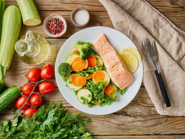 a plate of salmon, broccoli, cucumbers, tomatoes, and.