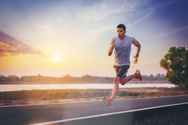 a man running down a road at sunset.