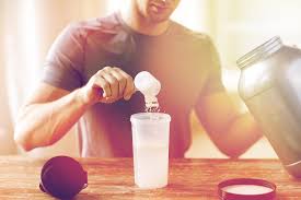 a man sitting at a table pouring something into a cup.