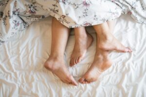 a couple of people laying in a bed under a blanket.