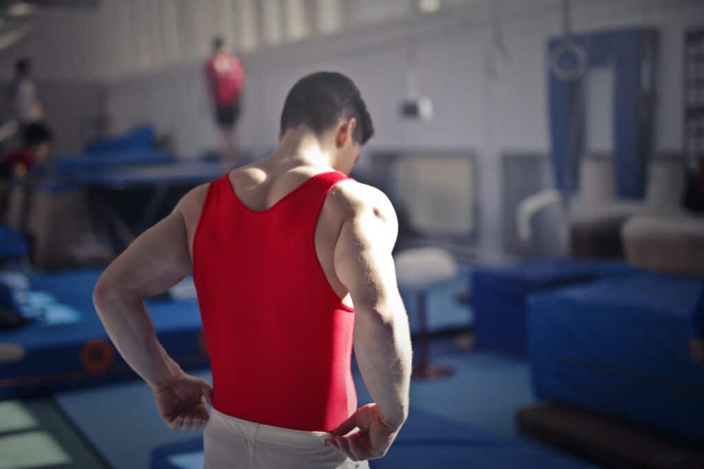 a man in a red tank top standing in a gym.